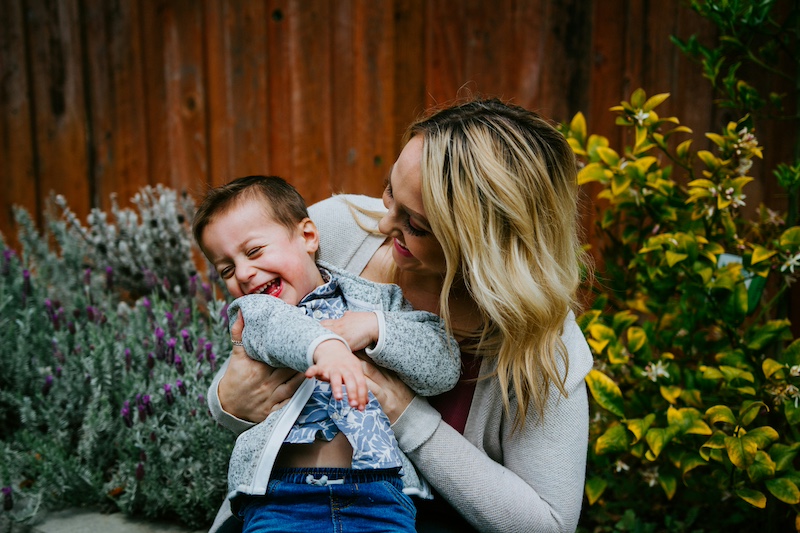 Mom holding young son laughing