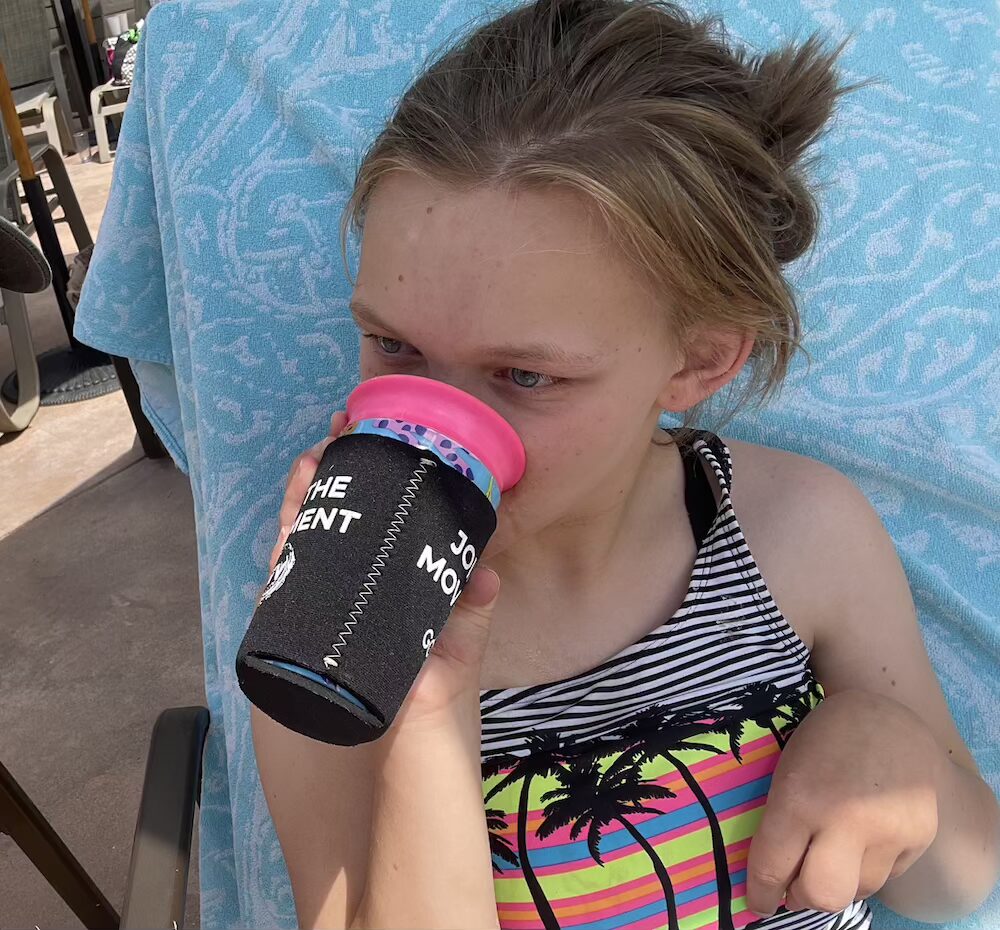 Teen drinking from sippy cup with koozie